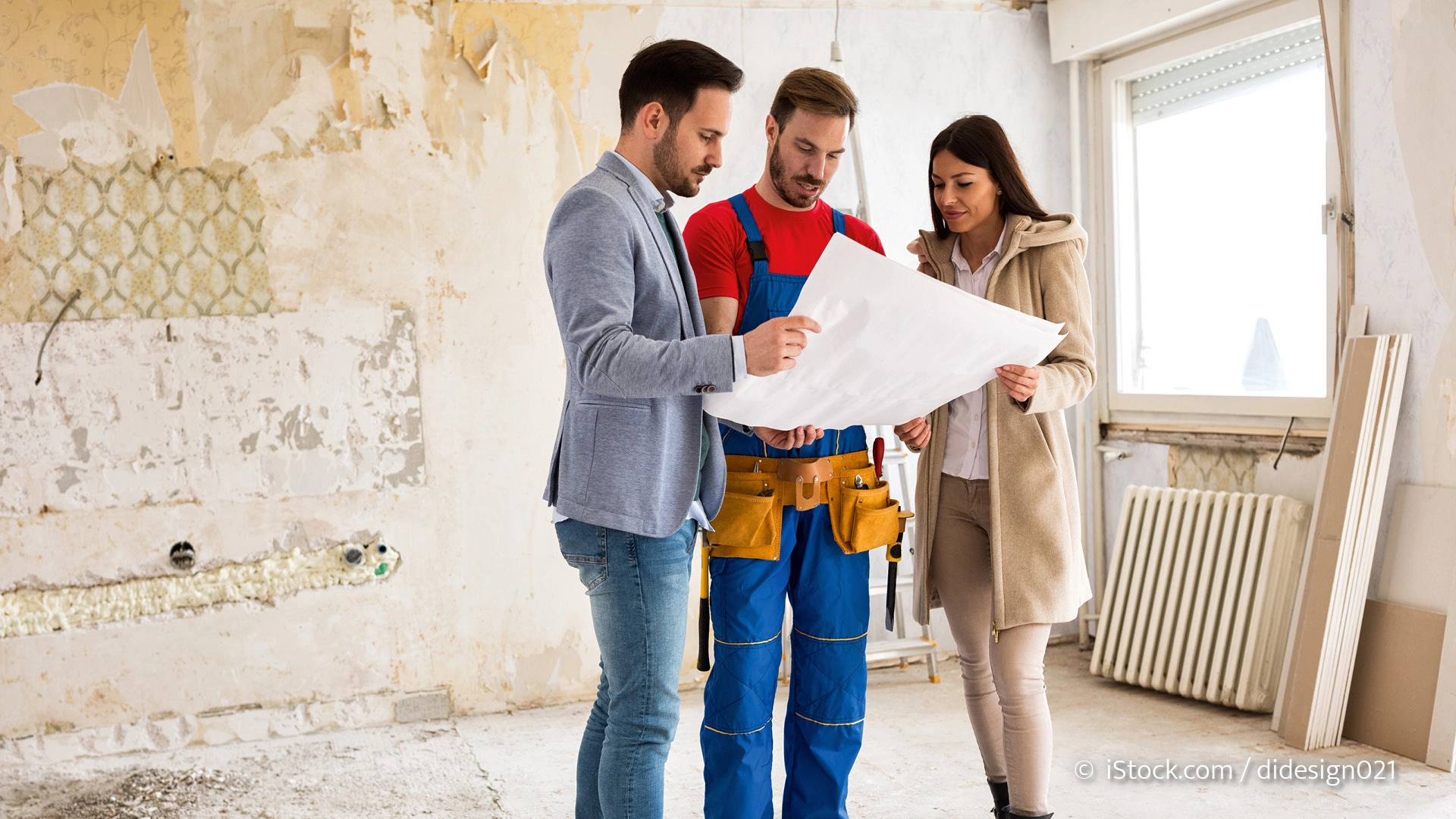 Mann und Frau sprechen mit Handwerker auf einer Baustelle im Haus